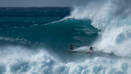 Two surfers share the giant wave at the famous Waimea Bay surf spot located on the North Shore of Oahu in Hawaii