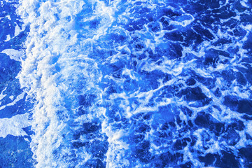 Deep blue glowing vibrant sea ocean waters wave with white foam from above. Travel cruise vacation...