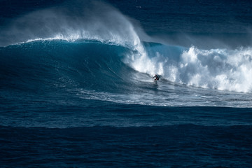 Surfer rides giant wave at the famous Waimea Bay surf spot located on the North Shore of Oahu in Hawaii