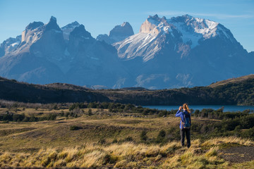 Woman hiker takes picture of the Cordillera Paine mountains in the Torres del Paine National Park in Chile