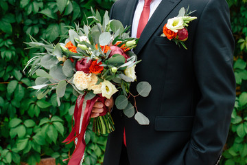Beautiful wedding bouquet in hands of the groom