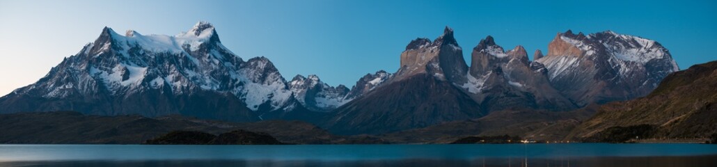 Panorama of Torres del Paine National Park with snow capped mountains (Cordillera Paine) and calm lake of Pehoe at late evening with stars in the sky. Chile