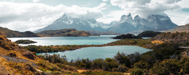 Torres del Paine National Park with snow capped mountains (Cordillera Paine) and the lake of Pehoe during sunny and windy weather. Chile - obrazy, fototapety, plakaty