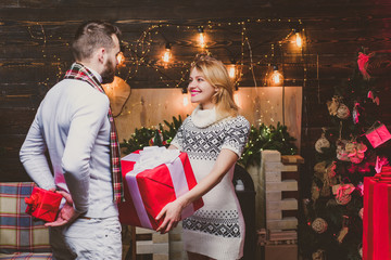 Happy woman and man are giving Christmas gifts to each other. Lovely happy couple. Christmas time. Hapiness.