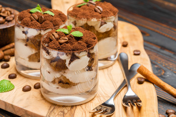 Classic tiramisu dessert in a glass on wooden background