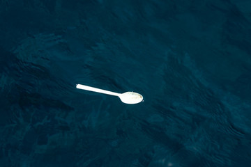 海を流れる使い捨てプラスチックのスプーン