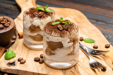 Classic tiramisu dessert in a glass on wooden background