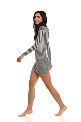 Smiling Young Woman Is Walking Barefoot In Striped Mini Dress