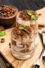 Classic tiramisu dessert in a glass on wooden background