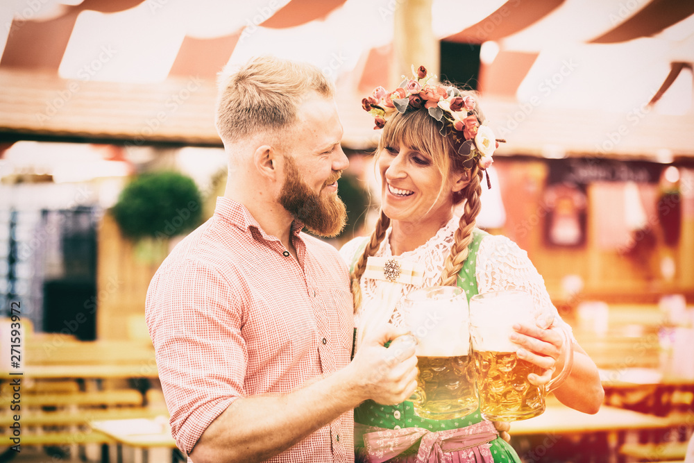 Wall mural Junges Paar Mann und Frau mit Dirndl und Lederhosen in Festezelt und Maß Bier