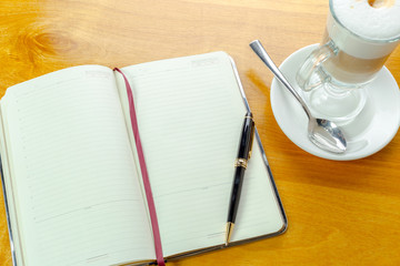 An open notebook with cup of coffee