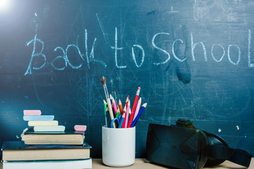 Concept back to school, virtual reality technology VR helmet. Pencils, books on the background of the school board