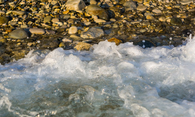 Fototapeta premium pebble stones on the sea beach, the rolling waves of the sea with foam