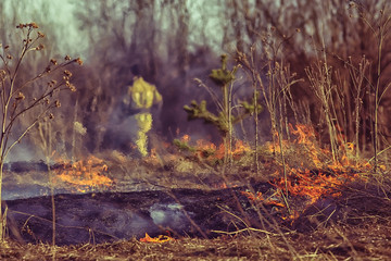firefighter puts out grass / forest fire, dry grass burns, wind blows