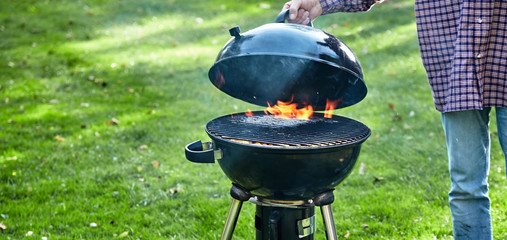 Person lifting the lid on a fire in a portable BBQ