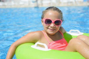 Happy little girl  with  life ring has fun in the swimming pool