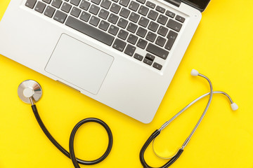 Stethoscope keyboard laptop computer isolated on yellow background. Modern medical Information technology and sofware advances concept. Computer and gadget diagnostics and repair. Flat lay top view