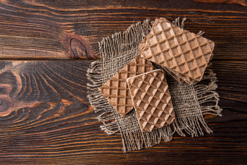 Chocolate waffles with milk filling on dark wooden background.