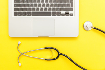 Stethoscope keyboard laptop computer isolated on yellow background. Modern medical Information technology and sofware advances concept. Computer and gadget diagnostics and repair. Flat lay top view