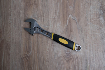 Adjustable wrench studio image. Tool adjustable wrench with the rubber handle on a blurred wooden background.