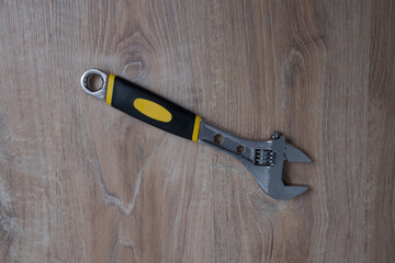 Adjustable wrench studio image. Tool adjustable wrench with the rubber handle on a blurred wooden background.
