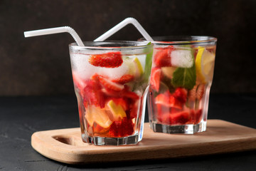 Strawberry Mojito. Cold summer mojito cocktail with strawberries, mint, lemon and ice in a glass on a black table. on a dark background