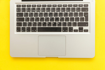 Keyboard laptop computer isolated on yellow desk background. Modern Information technology and sofware advances. Freelance home office programmer or designer workspace concept