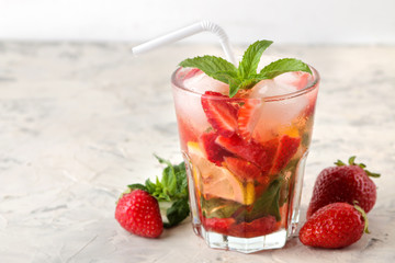 Strawberry Mojito. Cold summer mojito cocktail with strawberries, mint, lemon and ice in a glass on a bright table. summer refreshing drink.