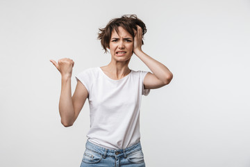 Fototapeta na wymiar Young pretty displeased shocked woman posing isolated over white wall background pointing to copyspace.
