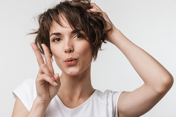 Fototapeta premium Excited happy woman posing isolated over white wall background showing peace gesture.