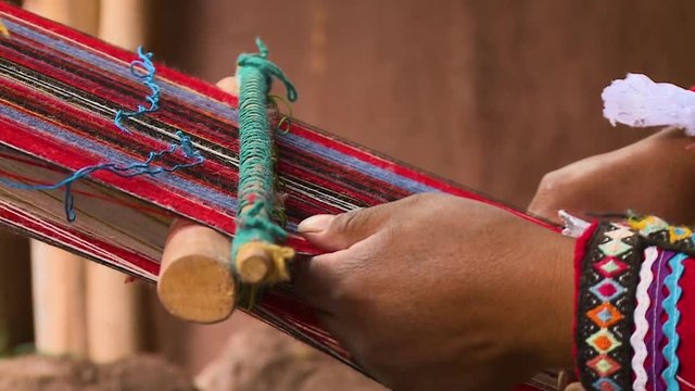 Extreme close-up still shot of a Peruvian woman weaving using a local hand loom, Andes, Peru