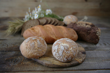  assortment of wheat and rye bread with flower in soft blur, close-up on a wooden rustic background
