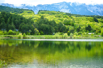 Scenic view of a mountain lake, with reflection on the water of the sky and mountains. Spring time.