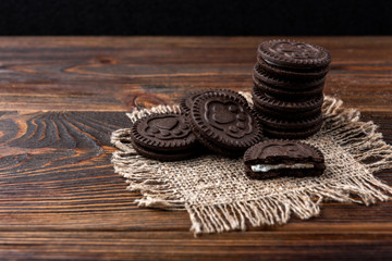 Obraz na płótnie Canvas Chocolate cookies with milk filling on dark wooden background.