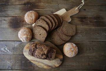still life with rye bread with sesame seeds and buns white bread on a wooden rustic background, top view, flat lay, with copy space for text