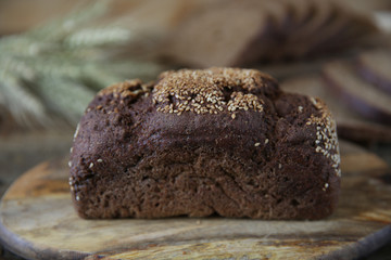 rye bread and ears of rye in soft blur background on wooden rustic background. Close-up.
