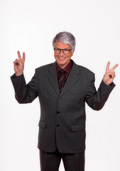 attractive mature European (Caucasian) slim businessman with short grey hair, grey suit, glasses, tie and purple shirt stands in front of white background and shows the 