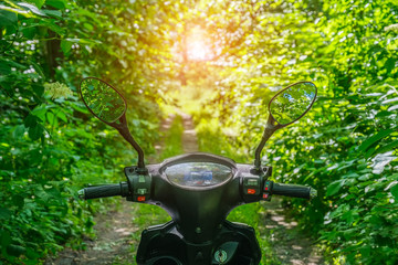 steering wheel of black electric scooter with reflection trees in the mirrors