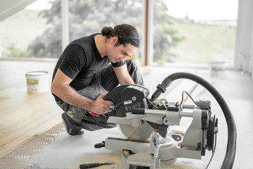 Handwerker schneidet Holzdiele mit der Kappsäge auf der Baustelle