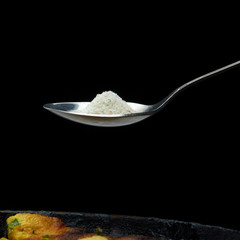 A LARGE SPOON OF SALT AROUND THE POT ON A DARK BACKGROUND