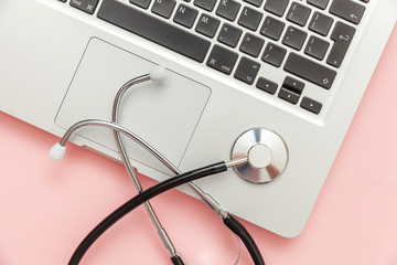 Stethoscope keyboard laptop computer isolated on pink background. Modern medical Information technology and sofware advances concept. Computer and gadget diagnostics and repair. Flat lay top view