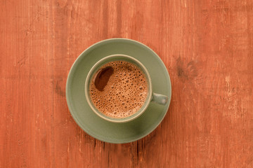 An overhead photo of a cup of coffee on a dark rustic wooden background with copyspace, toned image