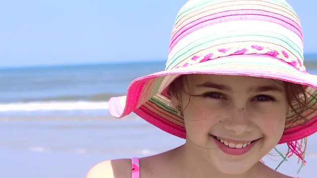 View of a beautiful teen girl wearing in colorful hat and swimsuit enjoying the view at tropical beach. Summer travel and vacation concept