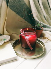summer and autumn composition a plaid book and a candle stand next to a beautiful pillow near the window Copy space Flat lay Selective focus