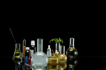 Medical jars with reagents and plant on a black background