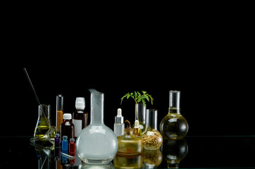 Obraz na płótnie Canvas Medical jars with reagents and plant on a black background