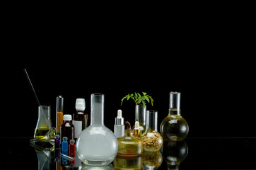 Medical jars with reagents and plant on a black background