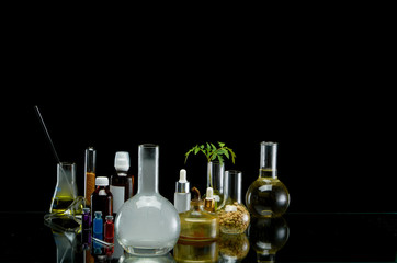 Medical jars with reagents and plant on a black background