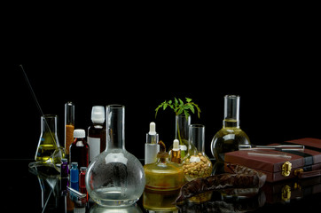 Medical jars with reagents and a plant with a leather suitcase on a black background
