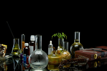 Medical jars with reagents and a plant with a leather suitcase on a black background